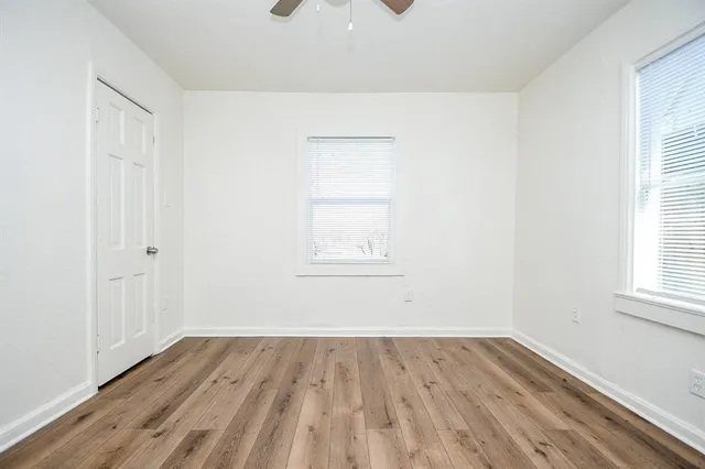 an empty room with wooden floor and windows
