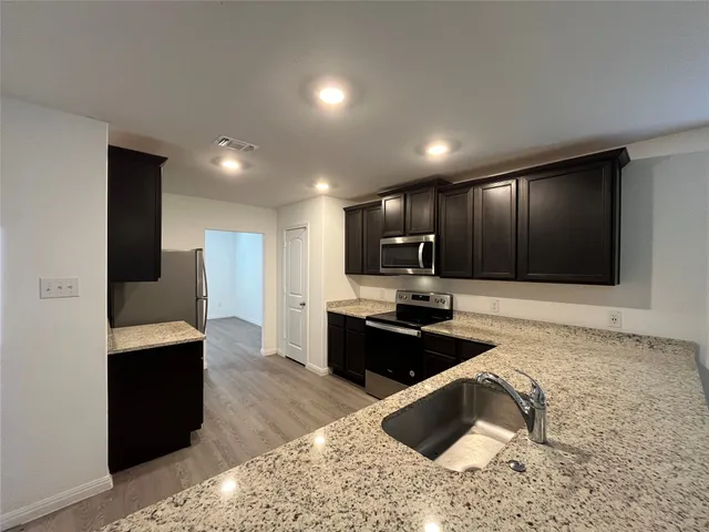 a kitchen with stainless steel appliances kitchen island granite countertop a refrigerator and a sink