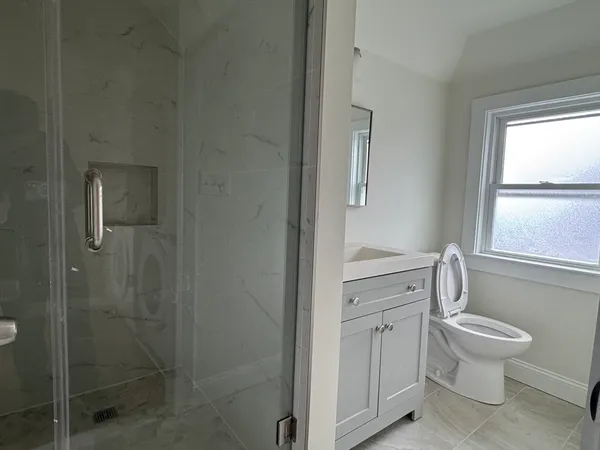 a bathroom with a granite countertop toilet a sink and a mirror