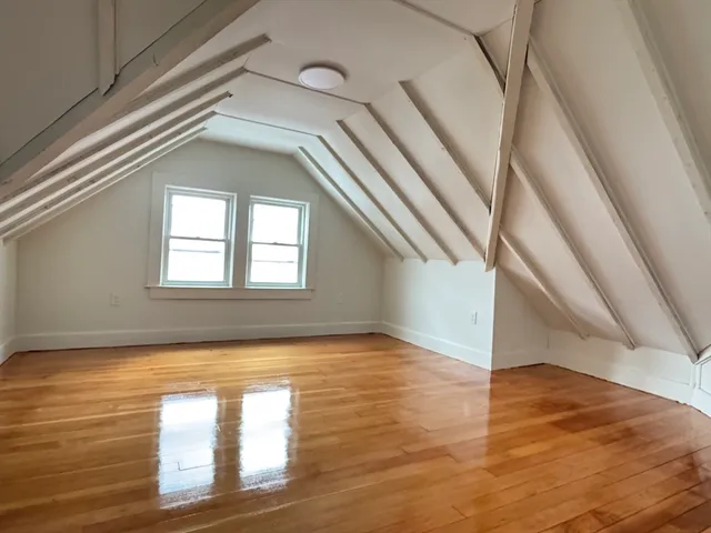 a view of an empty room with wooden floor and door
