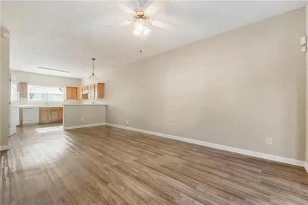 an empty room with wooden floor fan and windows