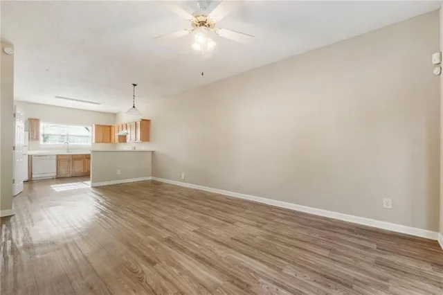 an empty room with wooden floor fan and windows