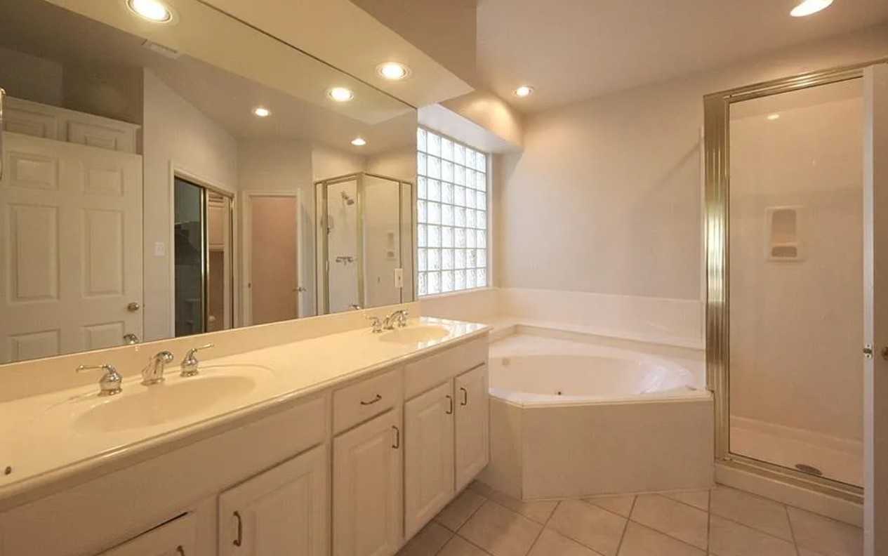 9405 Ashton Ridge Austin, TX 78750 - Photo 14 of 22 Indulge in a tranquil primary bath featuring a spacious corner tub and a bright glass block window.