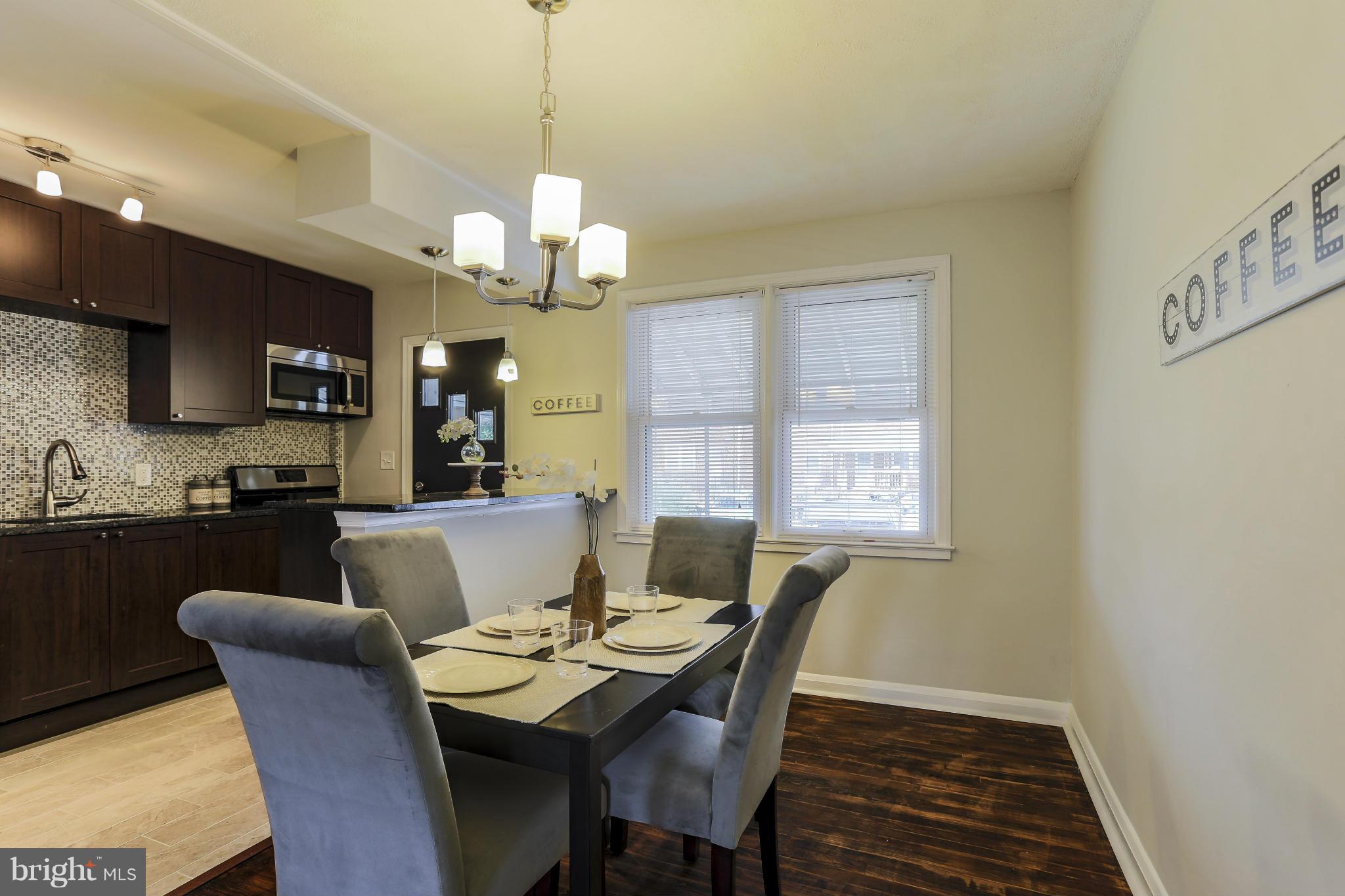 6923 Belclare Road Baltimore, MD 21222 - Photo 6 of 23 a view of a dining room with furniture a chandelier and wooden floor