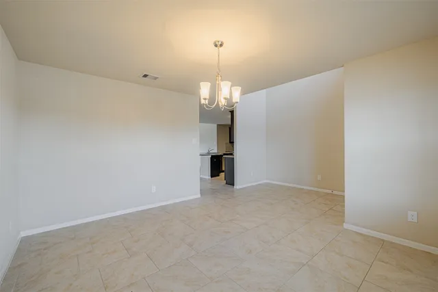 an empty room with chandelier and windows