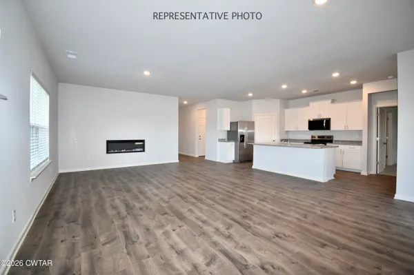 a view of kitchen with kitchen island a sink wooden floor and a refrigerator