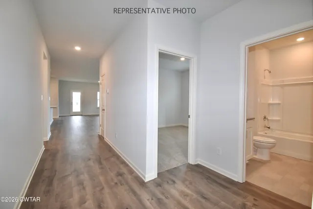 a view of a hallway with wooden floor and a bathroom