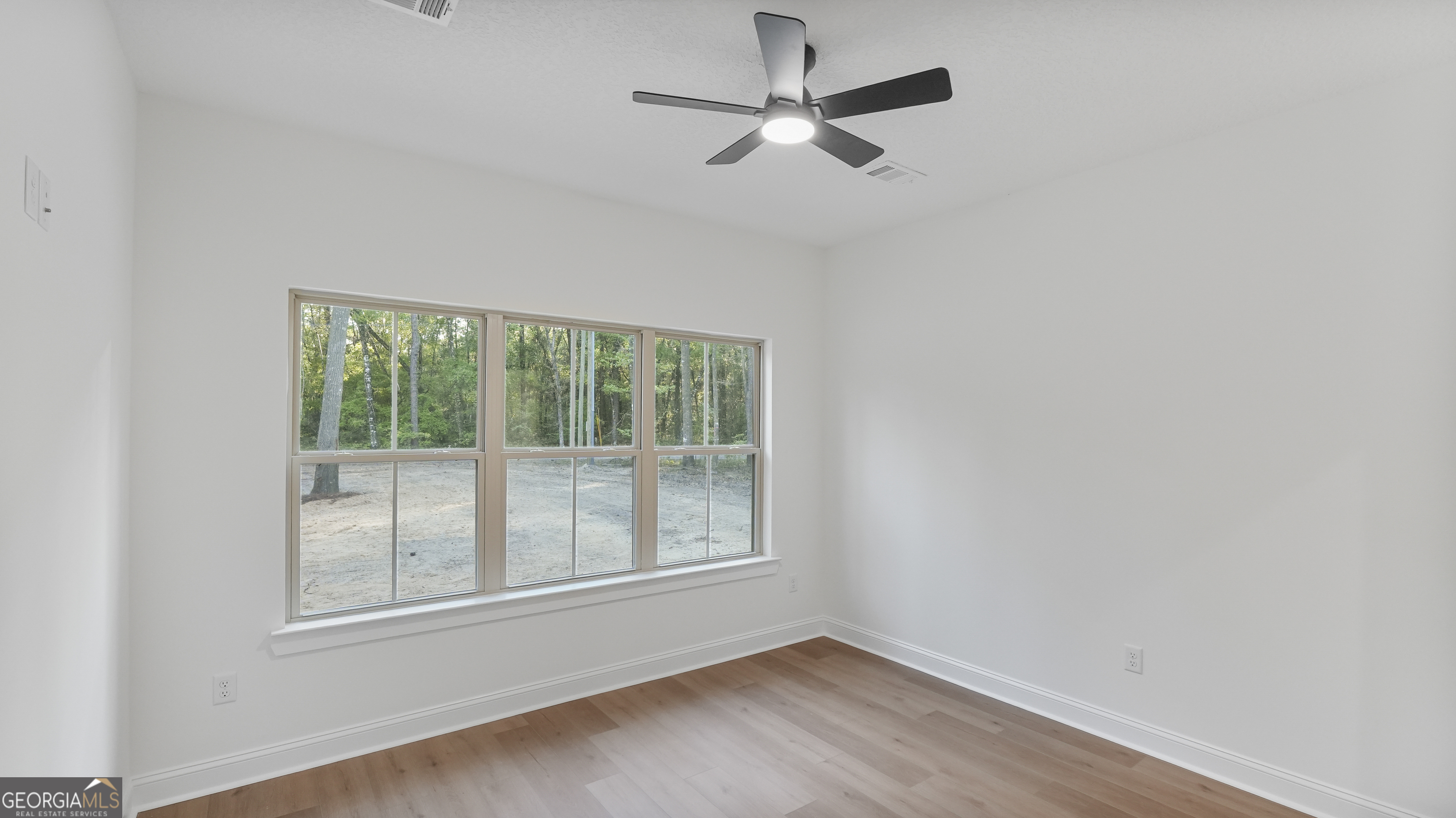 150 Lakeview Drive Jesup, GA 31545 - Photo 22 of 34 an empty room with wooden floor ceiling fan and windows
