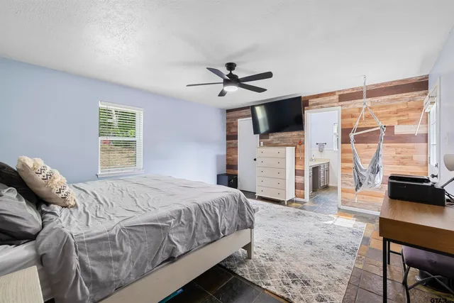 a bedroom with a bed a couch and a flat tv screen