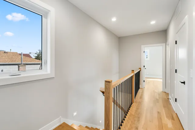 a view of a hallway with wooden floor and windows