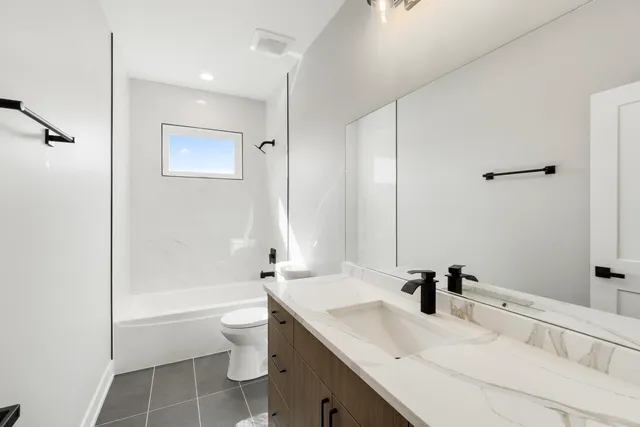a bathroom with a granite countertop sink a toilet and shower