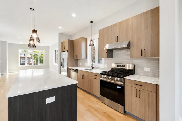 a kitchen with stainless steel appliances granite countertop a stove a sink and a refrigerator