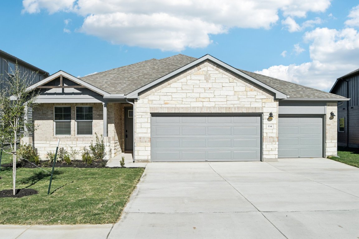 Ranch-style home with an attached garage, a front yard, driveway, and roof with shingles