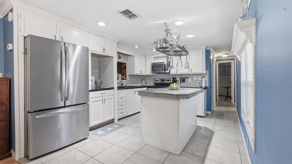 10565 Bessemer Street New Port Richey, FL 34654 - Photo 4 of 72 a kitchen with stainless steel appliances granite countertop a refrigerator a stove a sink and a refrigerator