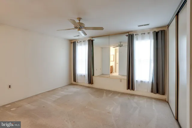 a view of a big room with windows and chandelier fan