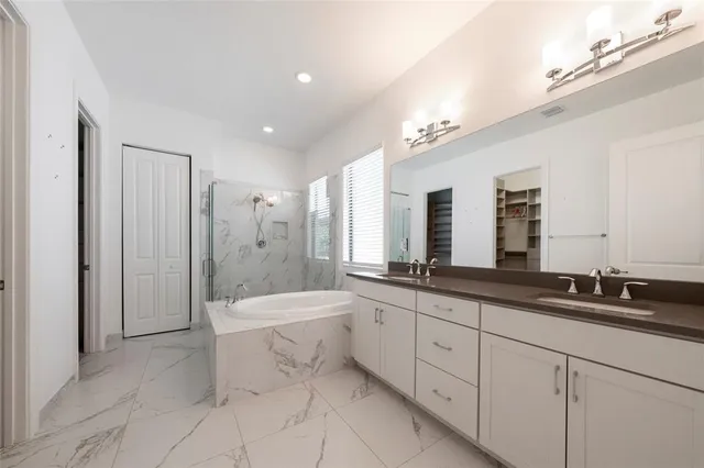 a large bathroom with a double vanity sink a large mirror and a bathtub