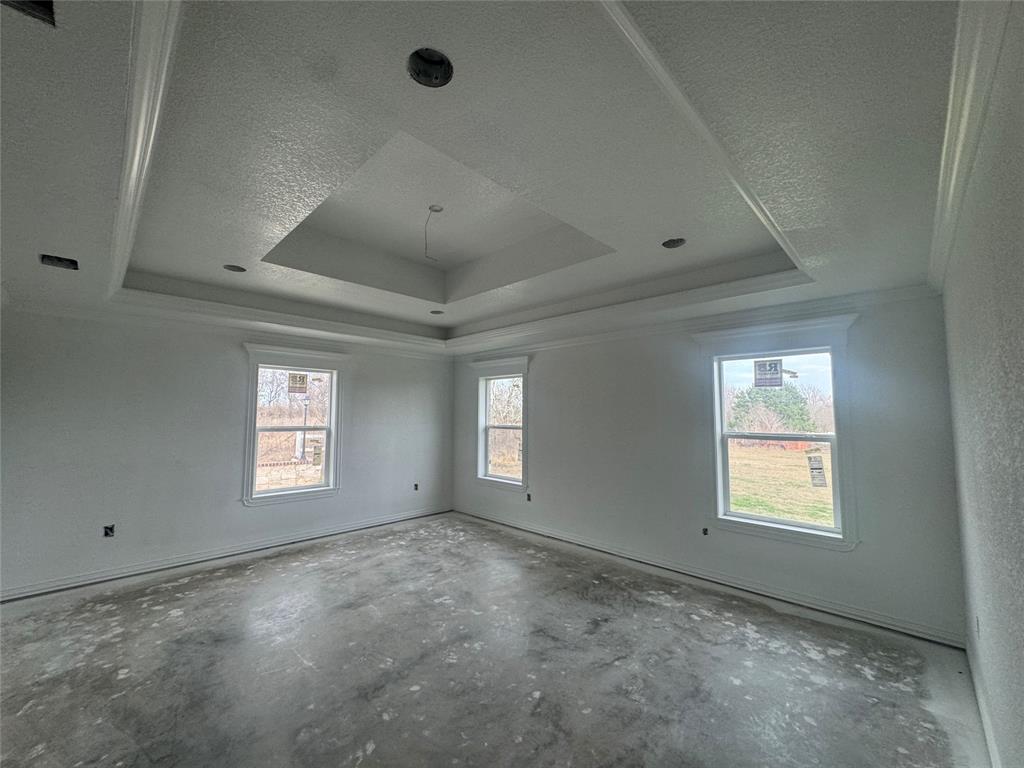 28296 Spring Valley Drive Kemp, TX 75143 - Photo 26 of 32 Empty room with a tray ceiling, unfinished concrete floors, ornamental molding, healthy amount of natural light, and a textured ceiling