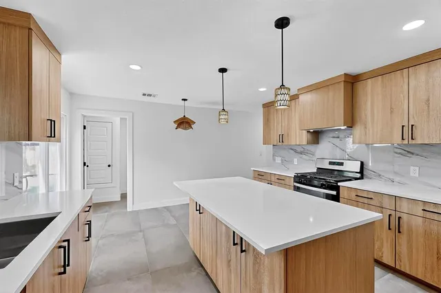 a kitchen with a stove a sink a refrigerator and a center island