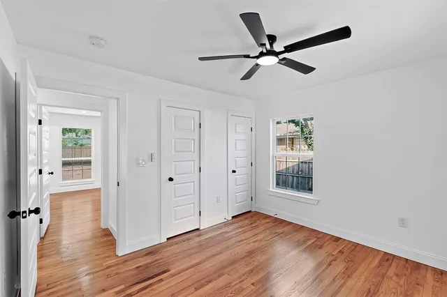 a view of empty room with wooden floor and ceiling fan