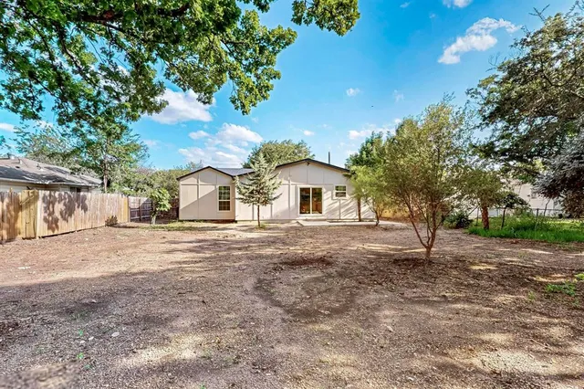 a front view of a house with a dirt yard and a large tree