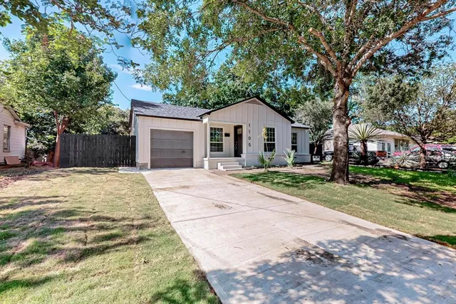a view of a house with a yard and large tree