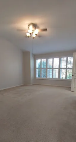 a view of an empty room with a chandelier fan and a fireplace