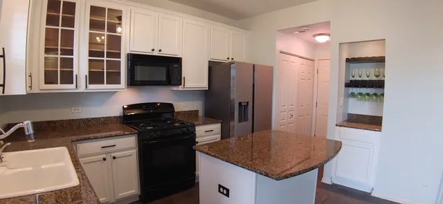 a kitchen with stainless steel appliances granite countertop a refrigerator a stove a sink and a microwave