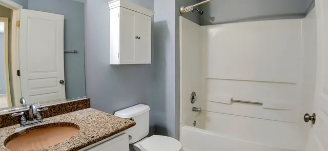 a bathroom with a granite countertop sink toilet and shower