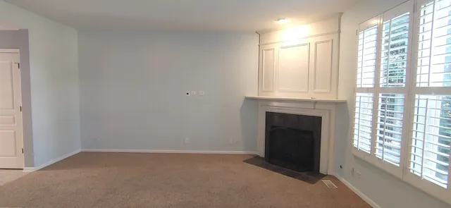 a view of an empty room with a fireplace and a window