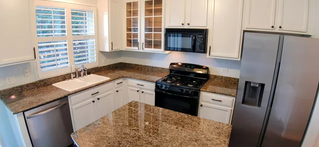 a kitchen with granite countertop a sink stove and refrigerator