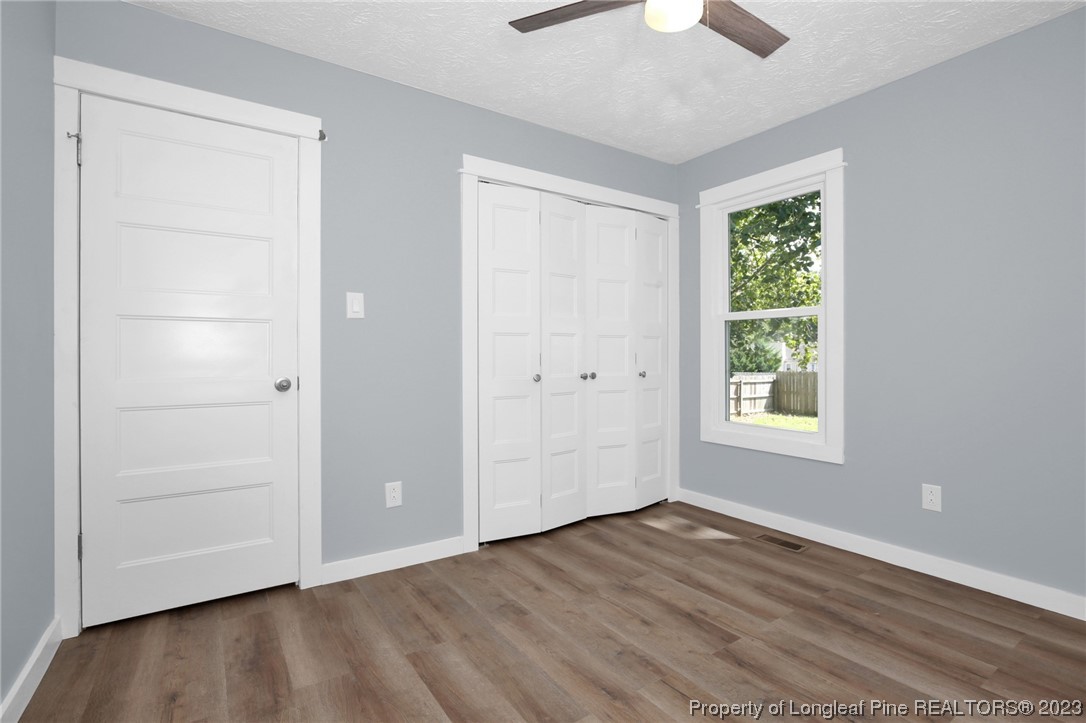 1163 Hoke Loop Road Fayetteville, NC 28314 - Photo 18 of 34 an empty room with wooden floor chandelier fan and windows