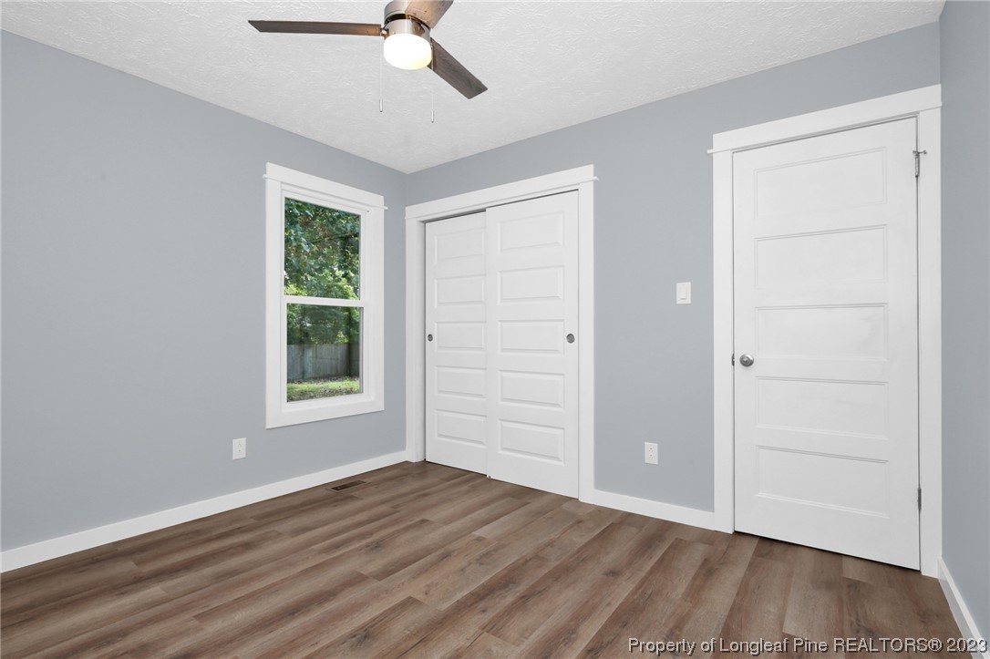 1163 Hoke Loop Road Fayetteville, NC 28314 - Photo 20 of 34 an empty room with wooden floor cabinet and windows