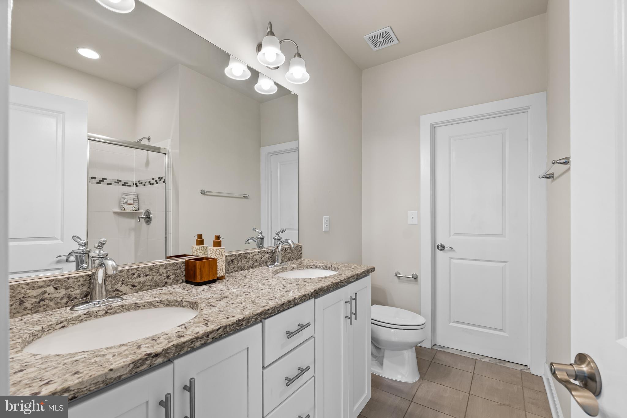 9780 Fields Road Gaithersburg, MD 20878 - Photo 16 of 37 a bathroom with a granite countertop sink a toilet and a mirror