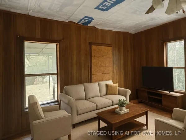 a living room with furniture a flat screen tv and a window