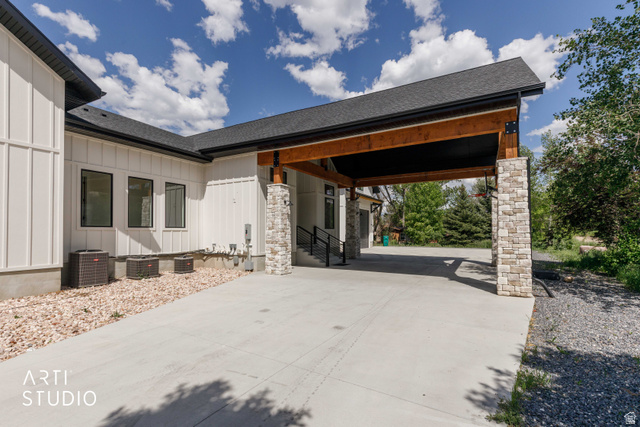 1188 South Old Trappers Loop Road Huntsville, UT 84317 - Photo 12 of 92 Covered carport featuring exposed wood beams and stacked stone columns, complemented by a board and batten exterior, dark-framed windows, and a gravel landscape bed