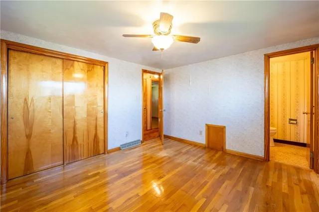 a view of an empty room with window and a kitchen