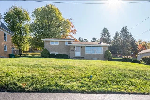 a front view of a house with a yard and trees