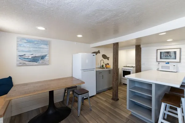a kitchen with a table chairs refrigerator and wooden floor