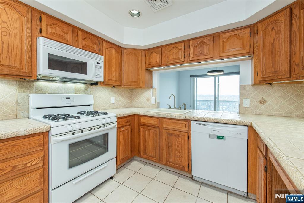 69 Amethyst Lane, Unit 283 Paterson, NJ 07501 - Photo 8 of 20 a kitchen with stainless steel appliances granite countertop a stove top oven a sink dishwasher and white cabinets with wooden floor