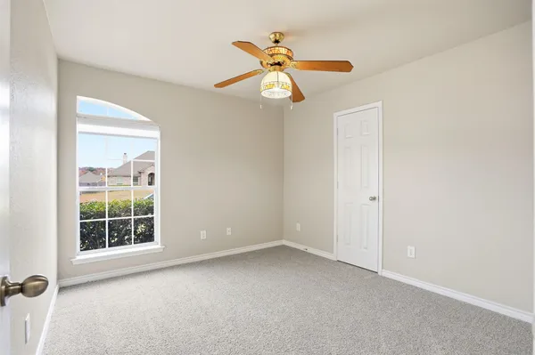 an empty room with windows and fan