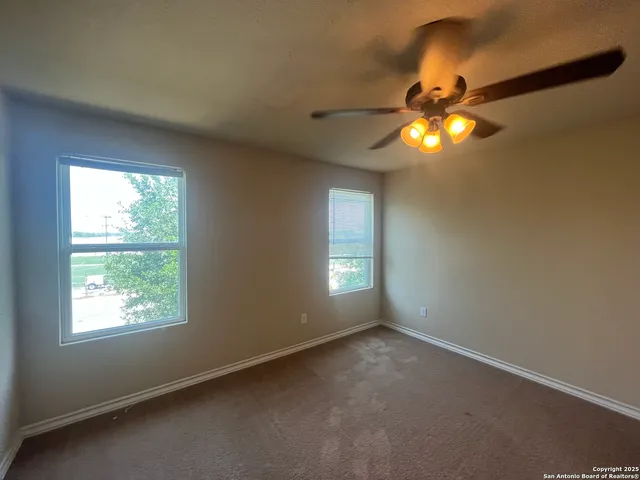 an empty room with windows and chandelier fan
