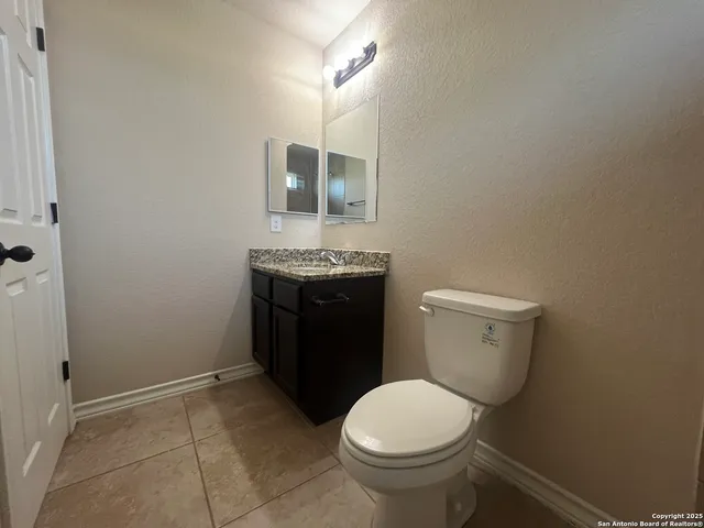 a bathroom with a granite countertop toilet and a sink