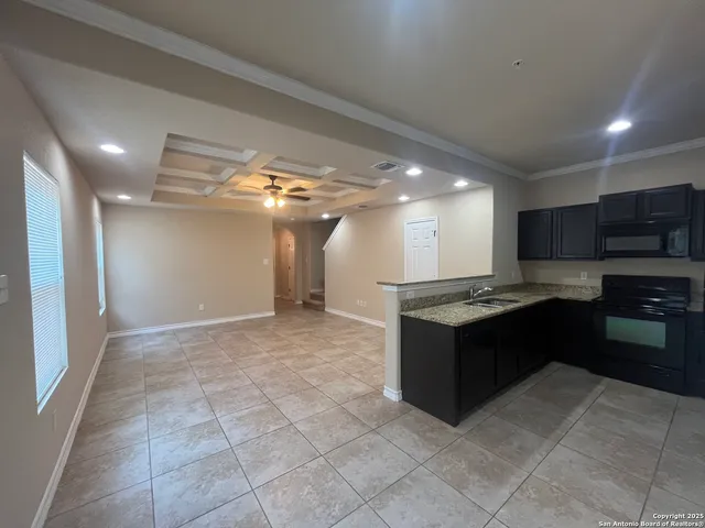 a large kitchen with granite countertop a stove top oven and cabinets