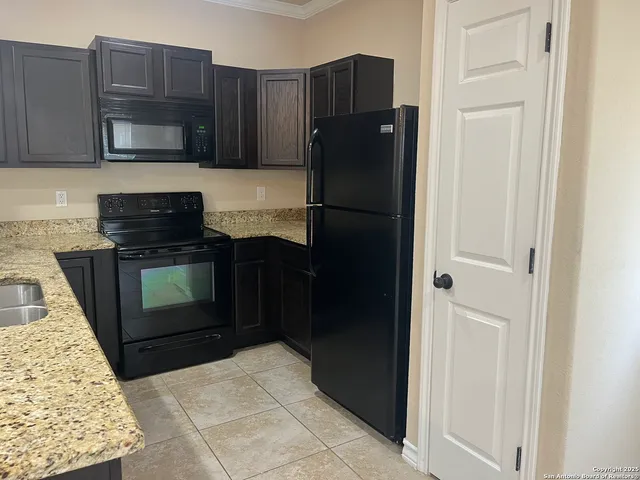 a kitchen with granite countertop a refrigerator and a stove top oven
