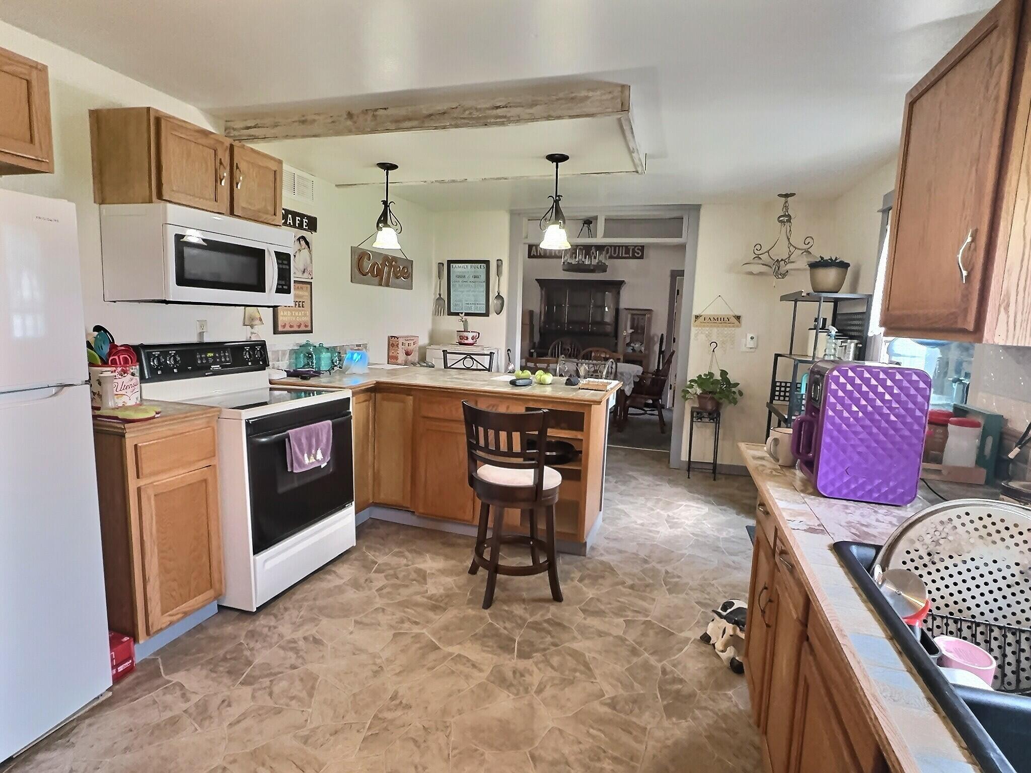 103 West Goss Street Kentland, IN 47951 - Photo 19 of 26 a open kitchen with stainless steel appliances granite countertop a stove top oven a sink a dining table and chairs with wooden floor