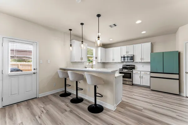 a view of a kitchen with kitchen island white cabinets and stainless steel appliances