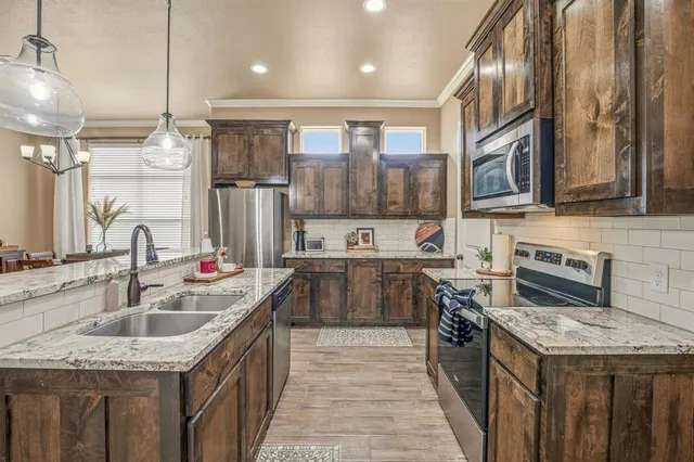 a kitchen with stainless steel appliances granite countertop a sink a stove and a wooden floors