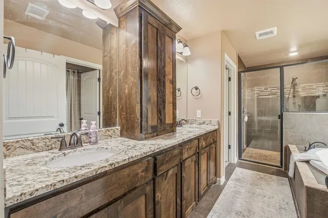 a bathroom with a granite countertop double vanity sink and mirror