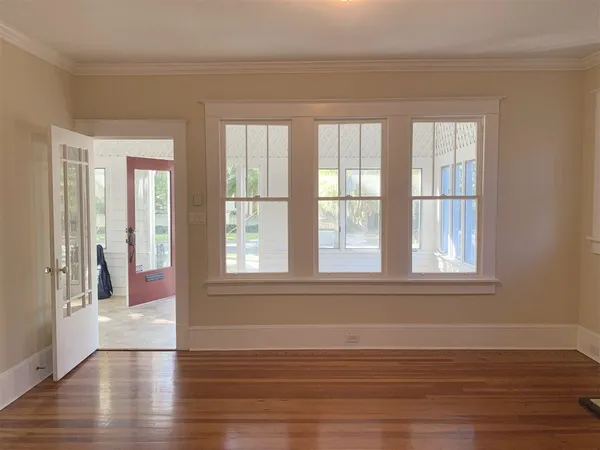 a view of an empty room with wooden floor and a window