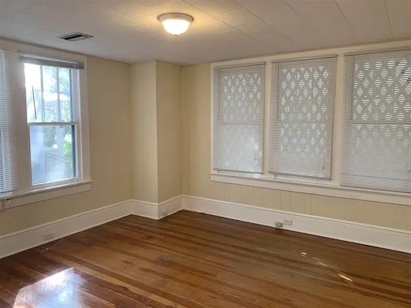 a view of empty room with wooden floor and fan